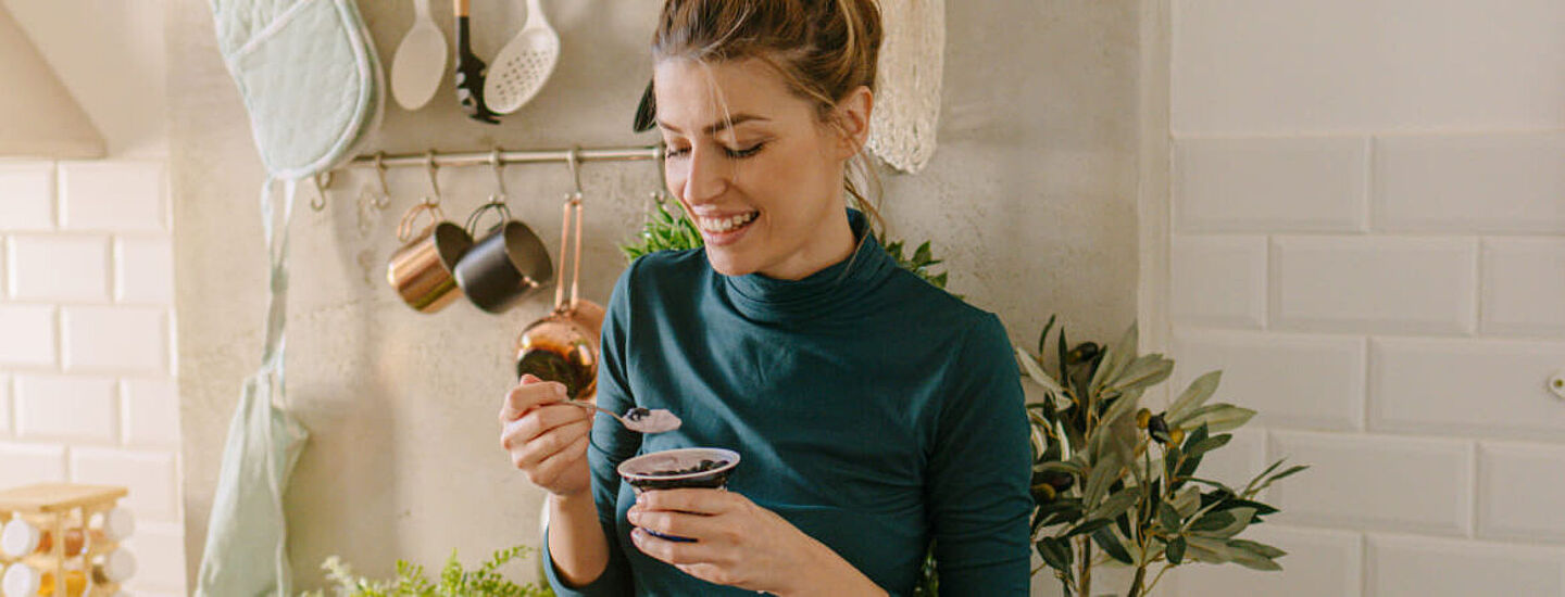 Una mujer come yogur en la cocina
