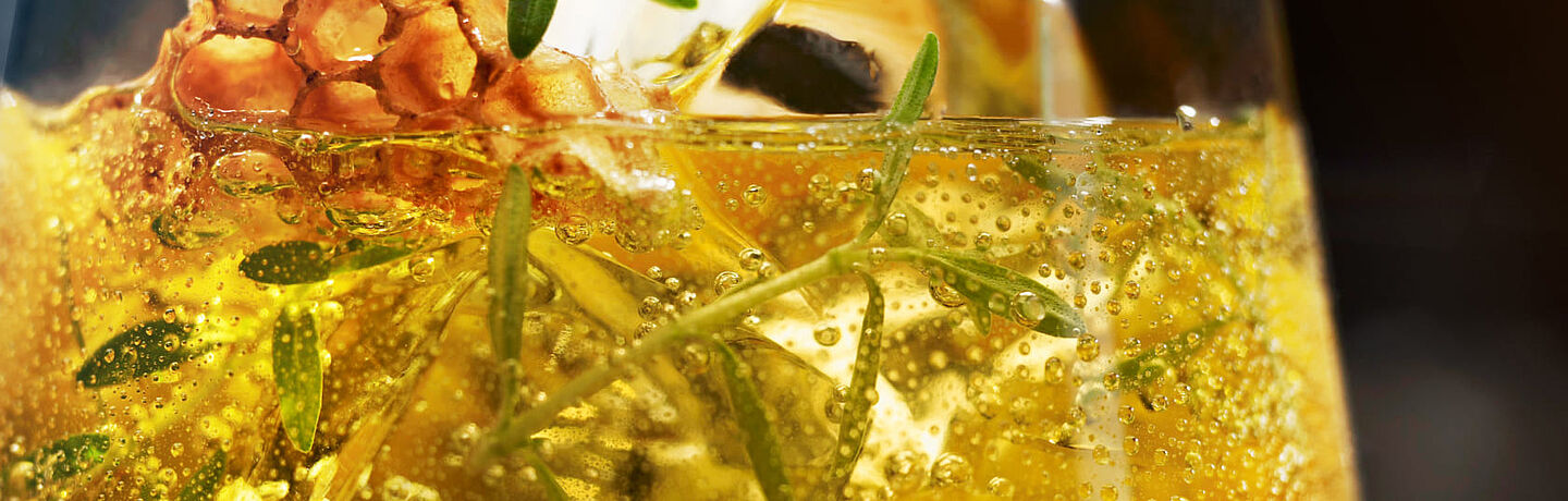 vaso con hielo, líquido amarillo y plantas